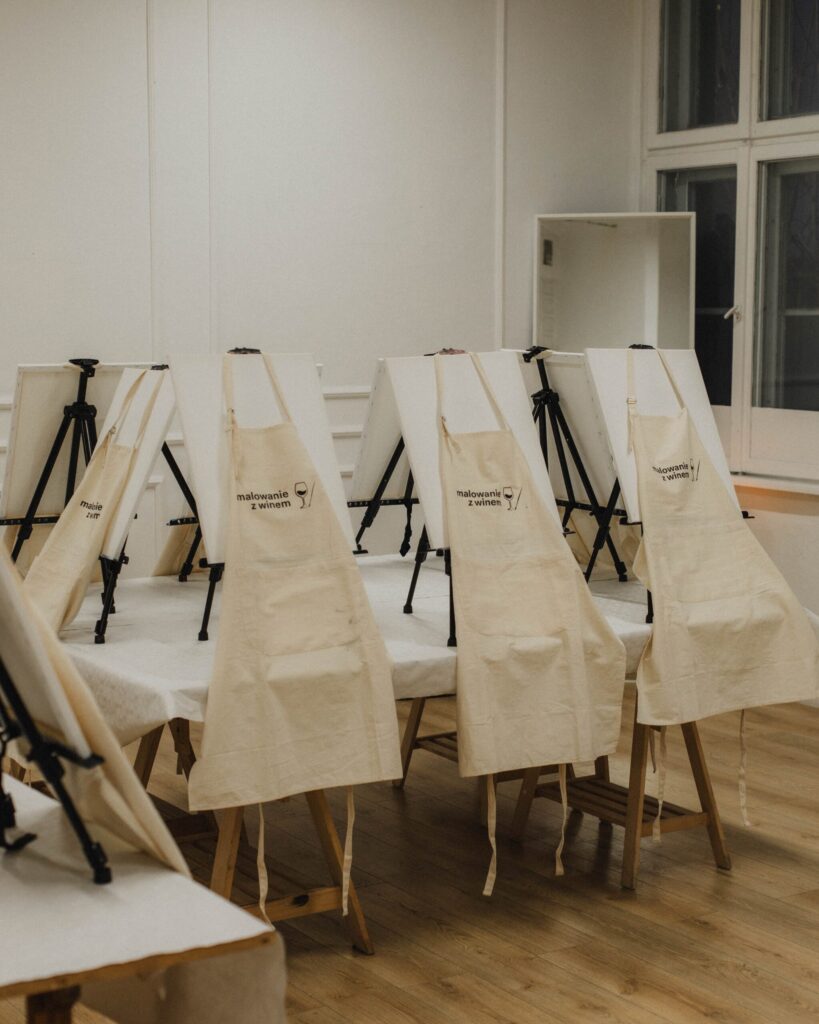 Uczestnicy warsztatów malowania przy winie malują obrazy na płótnie przy sztalugach